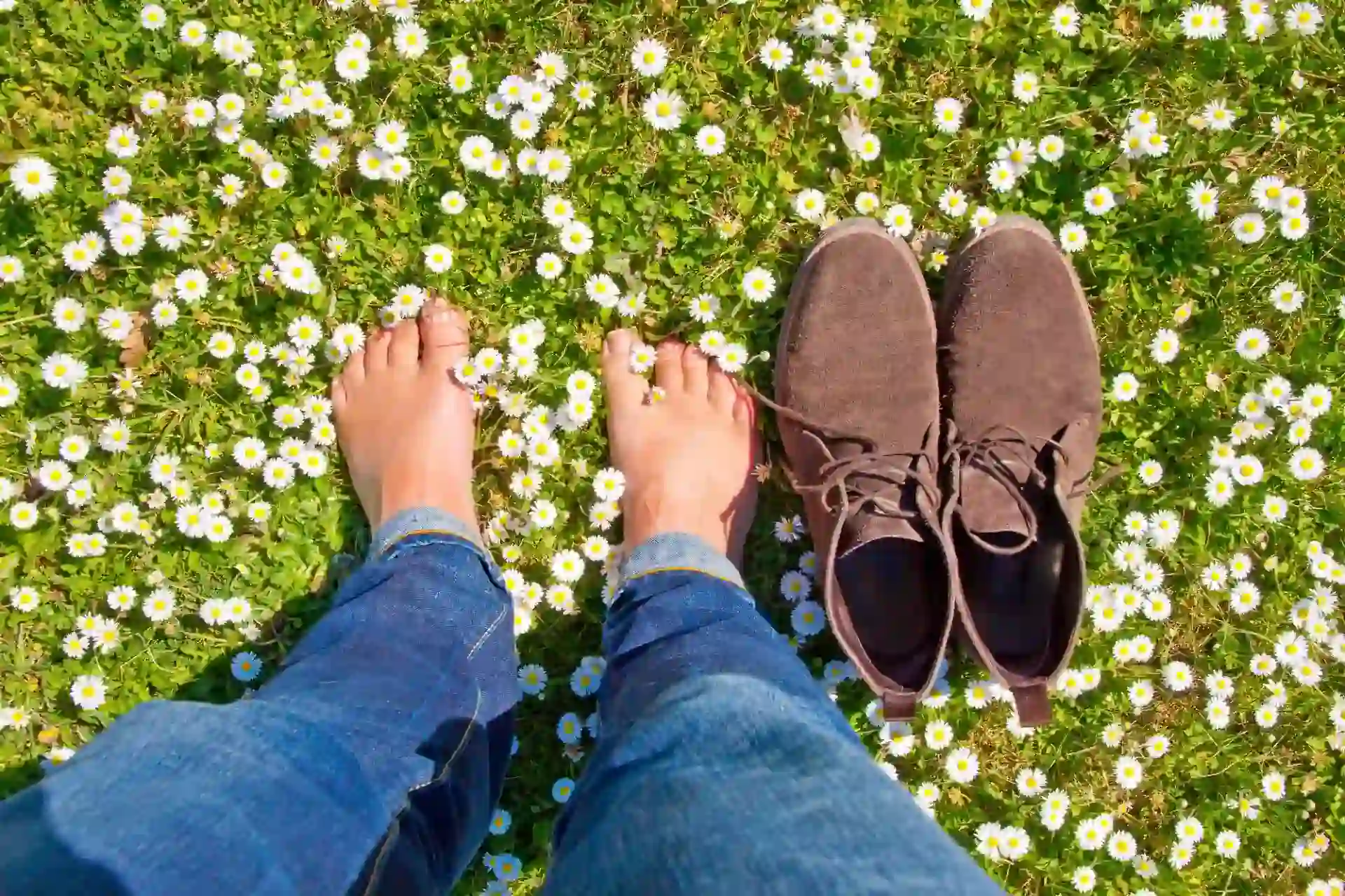 Sommer Schuh u Orthopädie GmbH - Person steht barfuß neben einem Paar Schuhen auf einer Blumenwiese